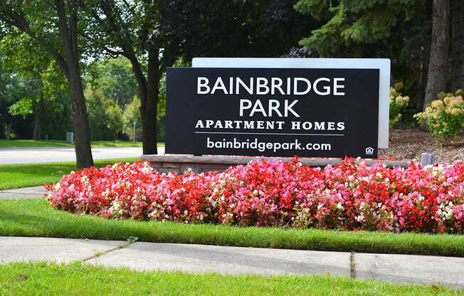 A sign for Bainbridge Park Apartment Homes is surrounded by flowers.