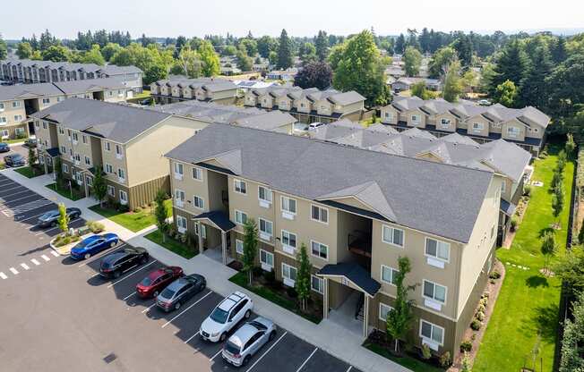 Apartment complex with a parking lot in front.