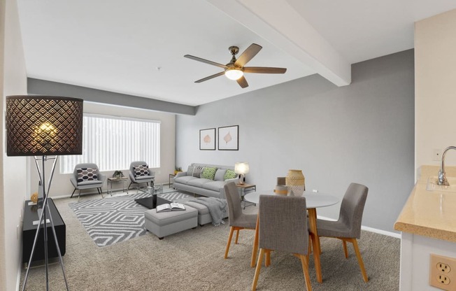 a living room with a couch table and chairs and a ceiling fan