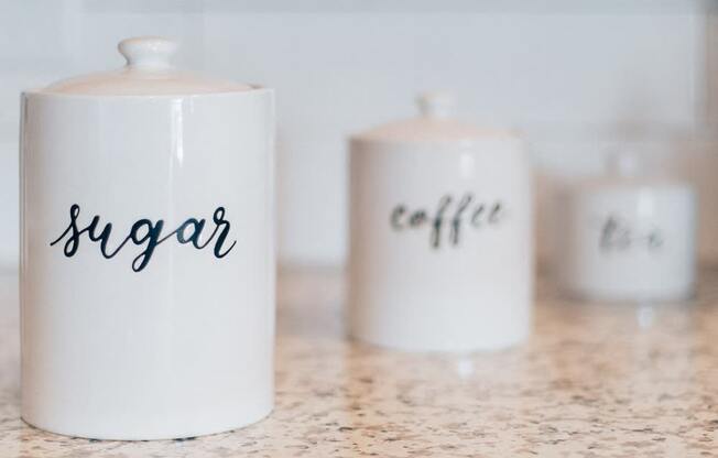 Three canisters, two of which are labeled sugar and coffee.