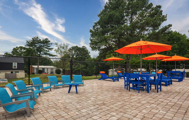 a patio with blue chairs and orange umbrellas and a table and chairs