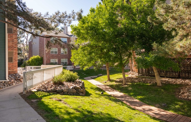 a sidewalk and trees in front of a brick building