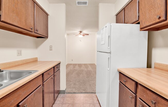 A kitchen with wooden cabinets and a white refrigerator.