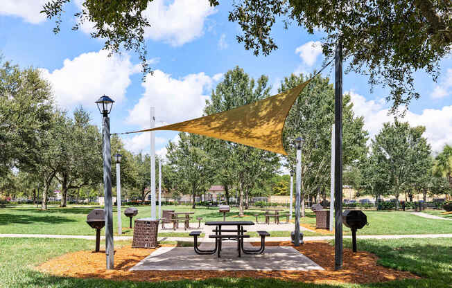 A park with a picnic table and a yellow canopy.