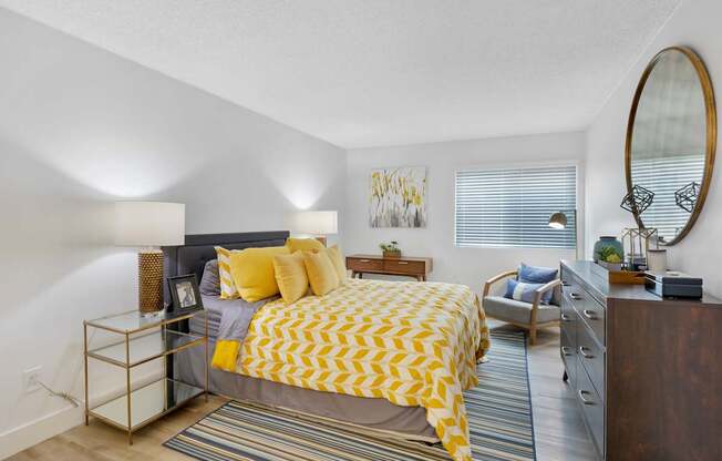 A bedroom with a bed, nightstand, and chair at Verandas Apartments, West Covina, CA, 91791