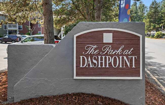 A sign that says "The Park at Dashpoint" is in front of a tree.