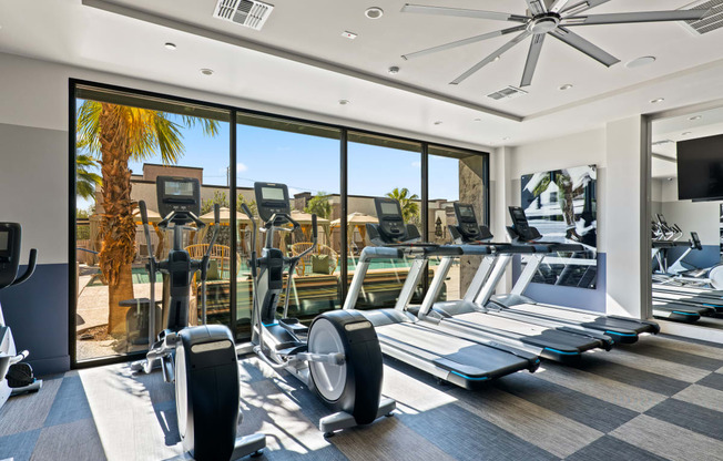 a gym with floor to ceiling windows and cardio equipment