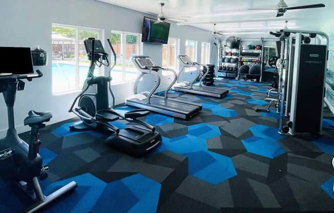 a gym with cardio equipment and a flat screen tv