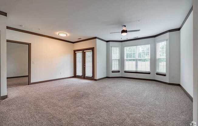 A room with a carpeted floor and a ceiling fan.