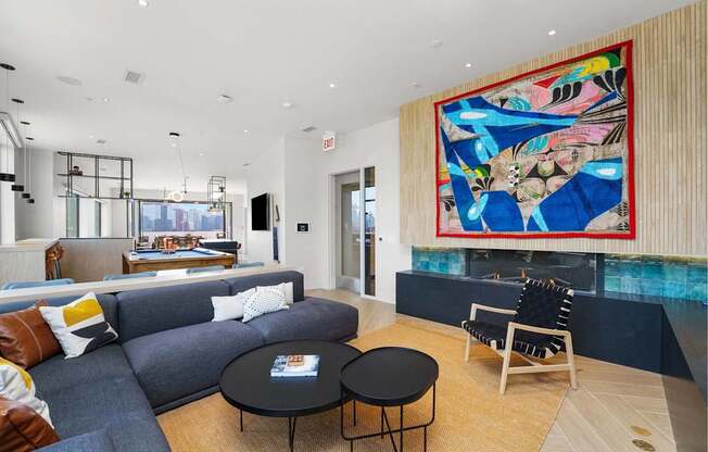 A living room with a grey couch, a black coffee table, and a large abstract painting on the wall.