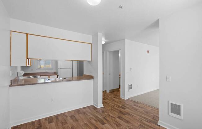 an empty living room and kitchen with white walls and wood floors