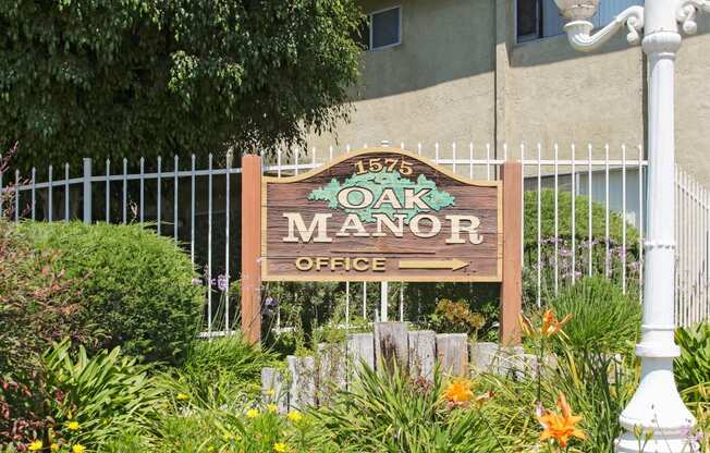 a sign for the oak manor office in front of a fence