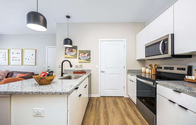 A kitchen with white cabinets and a granite countertop.