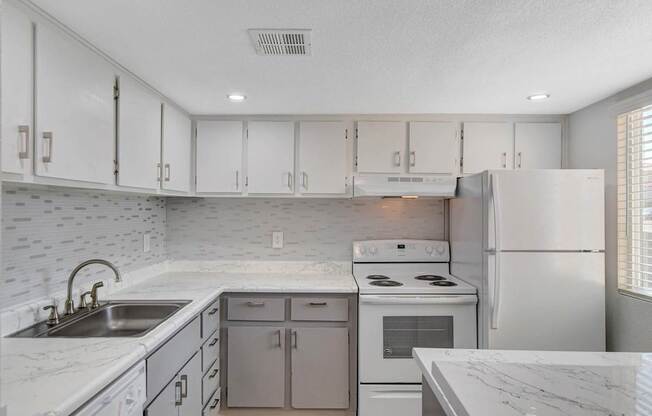 A kitchen with white cabinets and a marble countertop.
