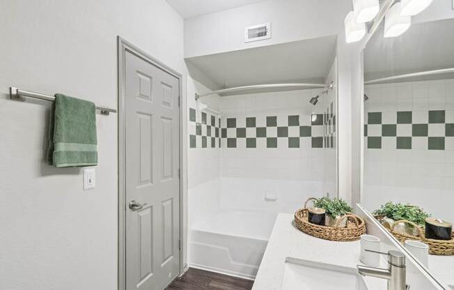 A bathroom with a white sink and a green and white checkered tile wall.