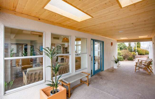 a porch with a bench and potted plants