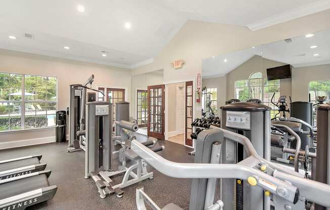 a gym with weights and cardio equipment in a building with windows