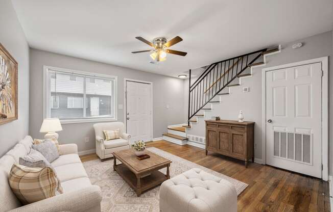 a living room with a staircase and a ceiling fan