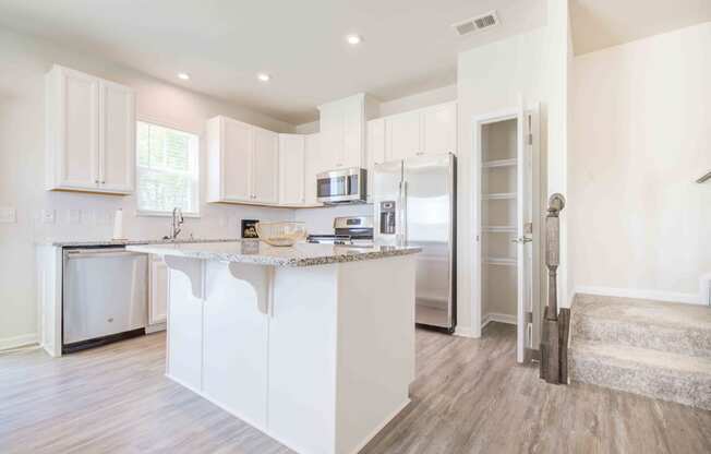 a white kitchen with an island and a stainless steel refrigerator