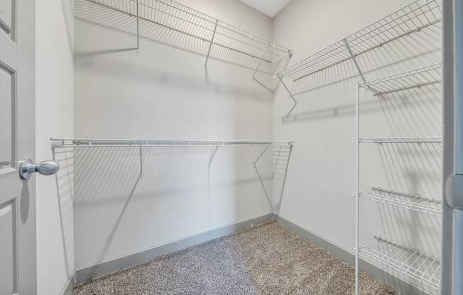 an empty closet with metal shelves in a room with a door