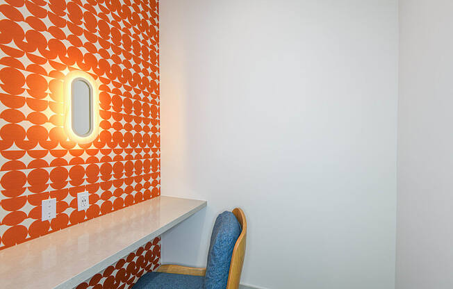 a chair in front of a orange wall with a small window