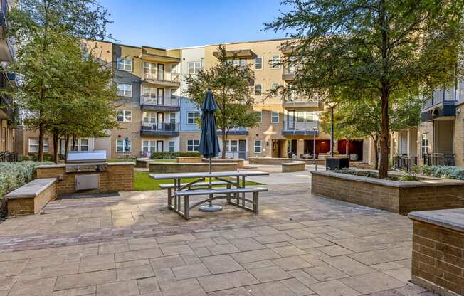 A sunny day at a courtyard with a picnic table and benches.