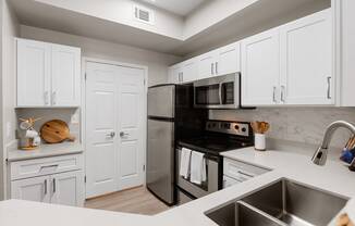 Kitchen with stainless steel appliances and white cabinets at Townhomes of Bent Tree