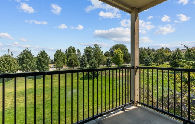 a balcony with a view of a grassy field and trees