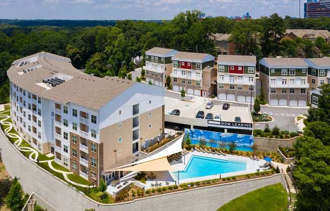 A large apartment complex with a swimming pool and a sign that says "Now Leasing".