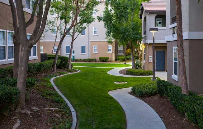 A pathway with a white line runs through a grassy area between two buildings.