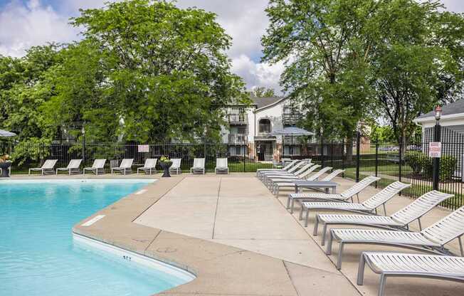 A pool surrounded by trees and lounge chairs