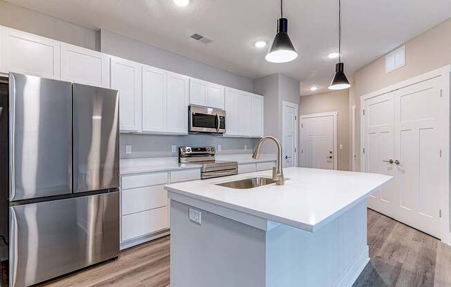 A modern kitchen with a stainless steel refrigerator and white cabinets.at Tiffany Flats, Columbus, 43231