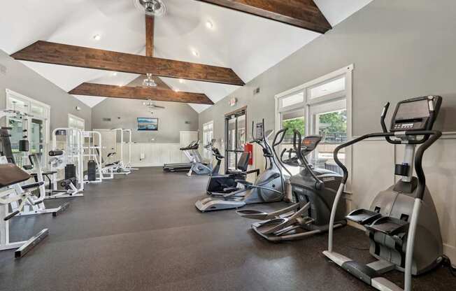 A spacious gym with a variety of exercise equipment and a wooden beam ceiling.