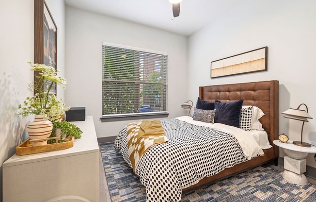 A bedroom with a bed, nightstand, and window.