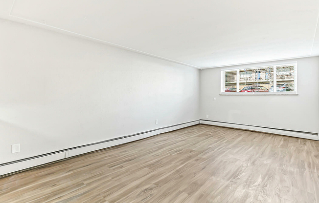 Bright and spacious empty room with elegant hardwood floors and large windows, perfect for customization.
