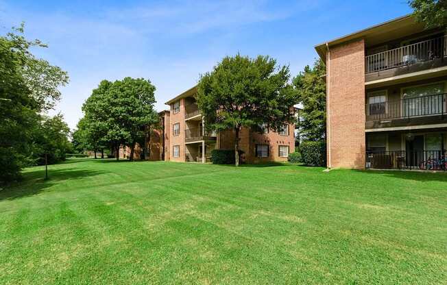 A large grassy area in front of a brick building with balconies.