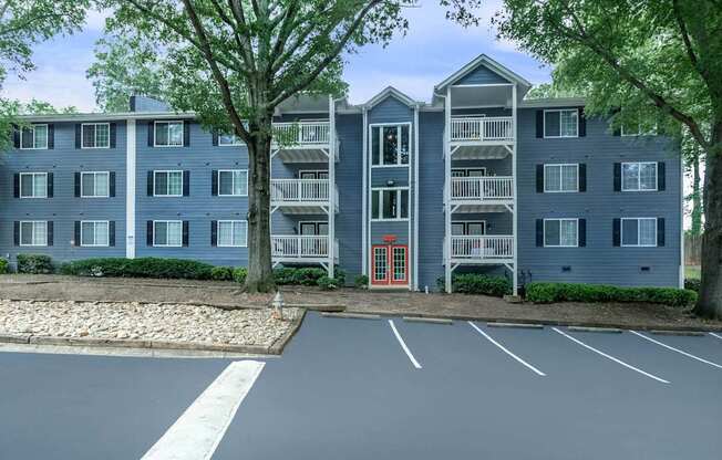 A large grey apartment building with a red door in front.