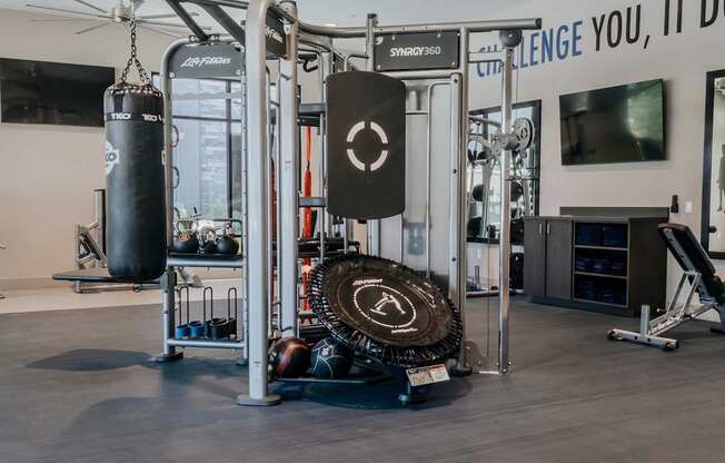 Multi-station strength training machine with kettlebells and ropes, punching bag and ball throw.