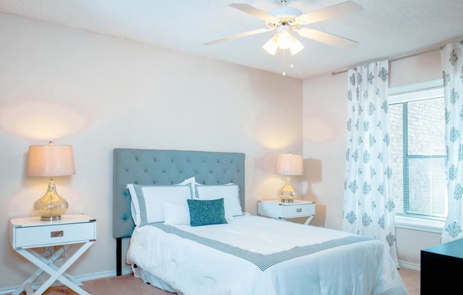 Model bedroom with a bed and a ceiling fan at Chisholm Place Apartments in Plano, TX