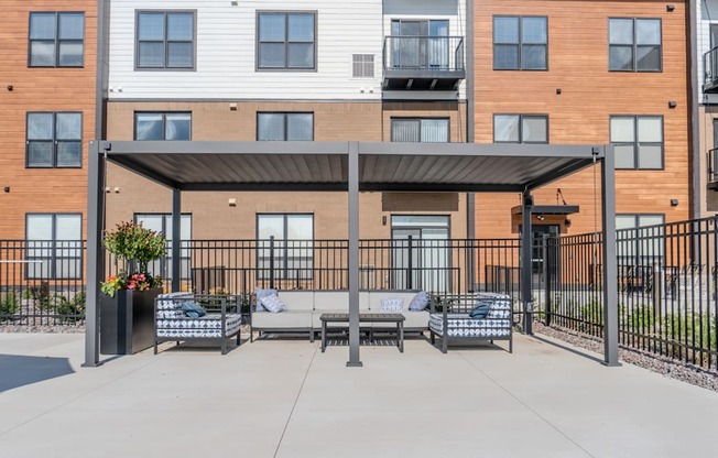 A patio area with a black metal railing and a black awning.