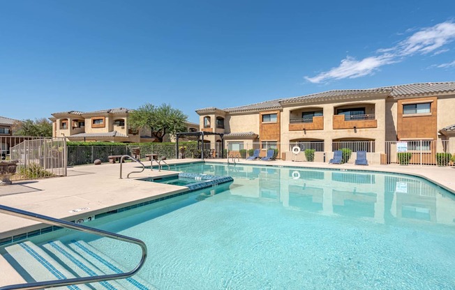 A swimming pool in front of a building with a clear blue sky.