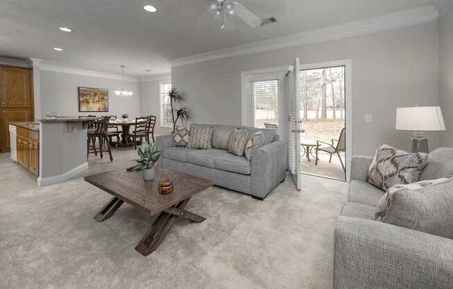A living room with a grey couch, a wooden coffee table, and a dining table with chairs.
