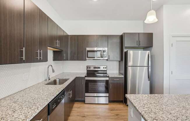 A modern kitchen with dark wood cabinets and stainless steel appliances.