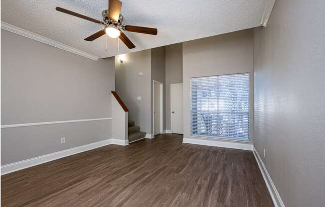 A room with a ceiling fan and wooden flooring.