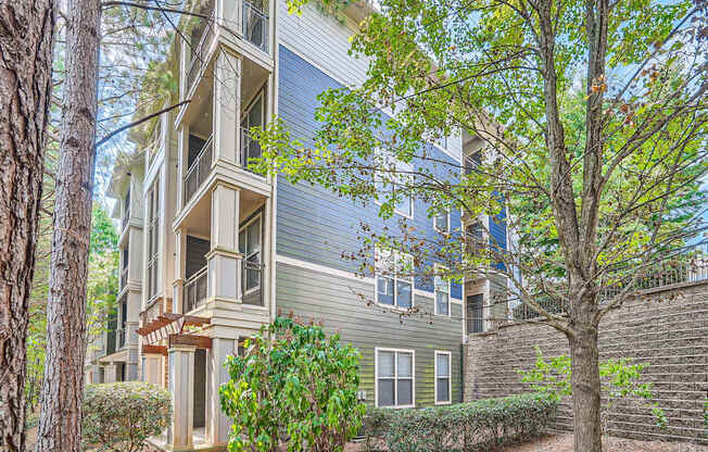 A tree in front of a grey building with a balcony.