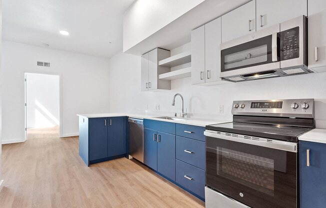 a kitchen with blue cabinets and a stove and a microwave