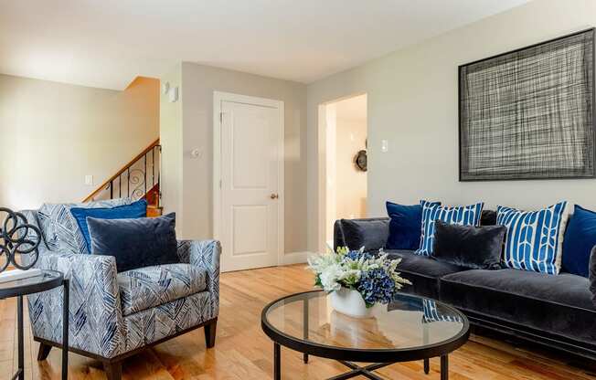 A living room with a black couch and a blue and white patterned chair.