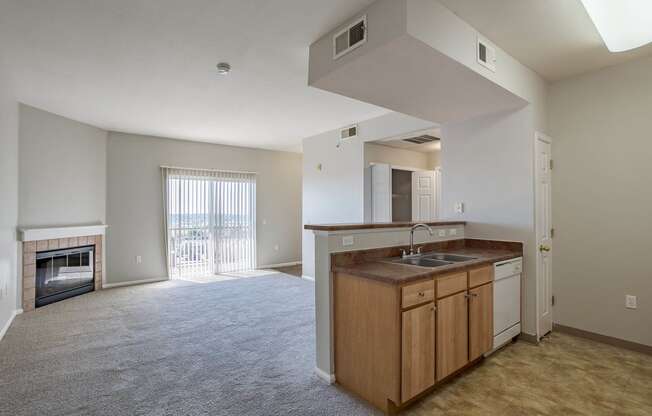 an empty living room with a kitchen and a fireplace at Stetson Meadows Apartments, Colorado Springs, CO