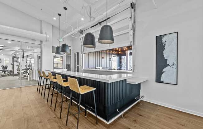 a long bar with chairs in a restaurant with white walls and wood floors