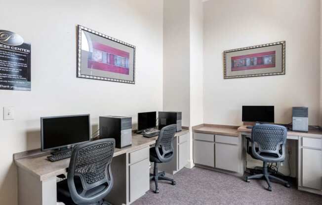 Business Center with computer lab, three chairs, framed photos on the walls, and tan and cream desks